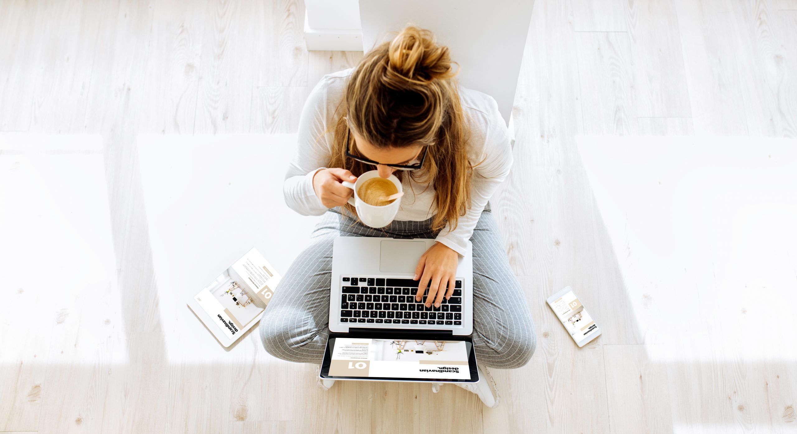 top view of woman working on responsive scandinavian interior design magazine and drinking coffee